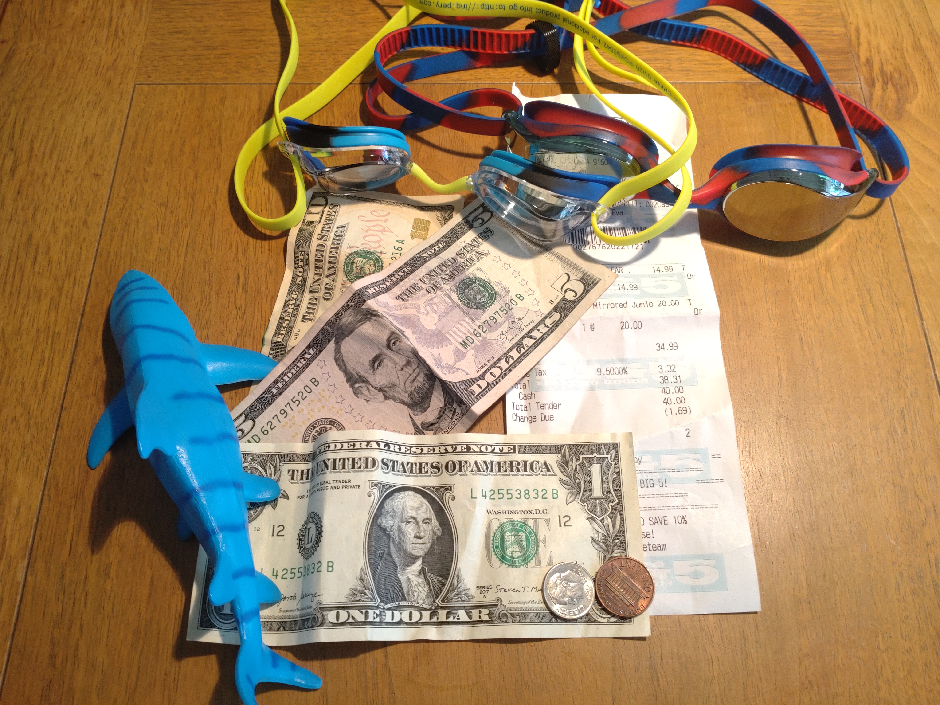 Toy shark, sixteen dollars in cash, two pairs of kids goggles and a receipt.
