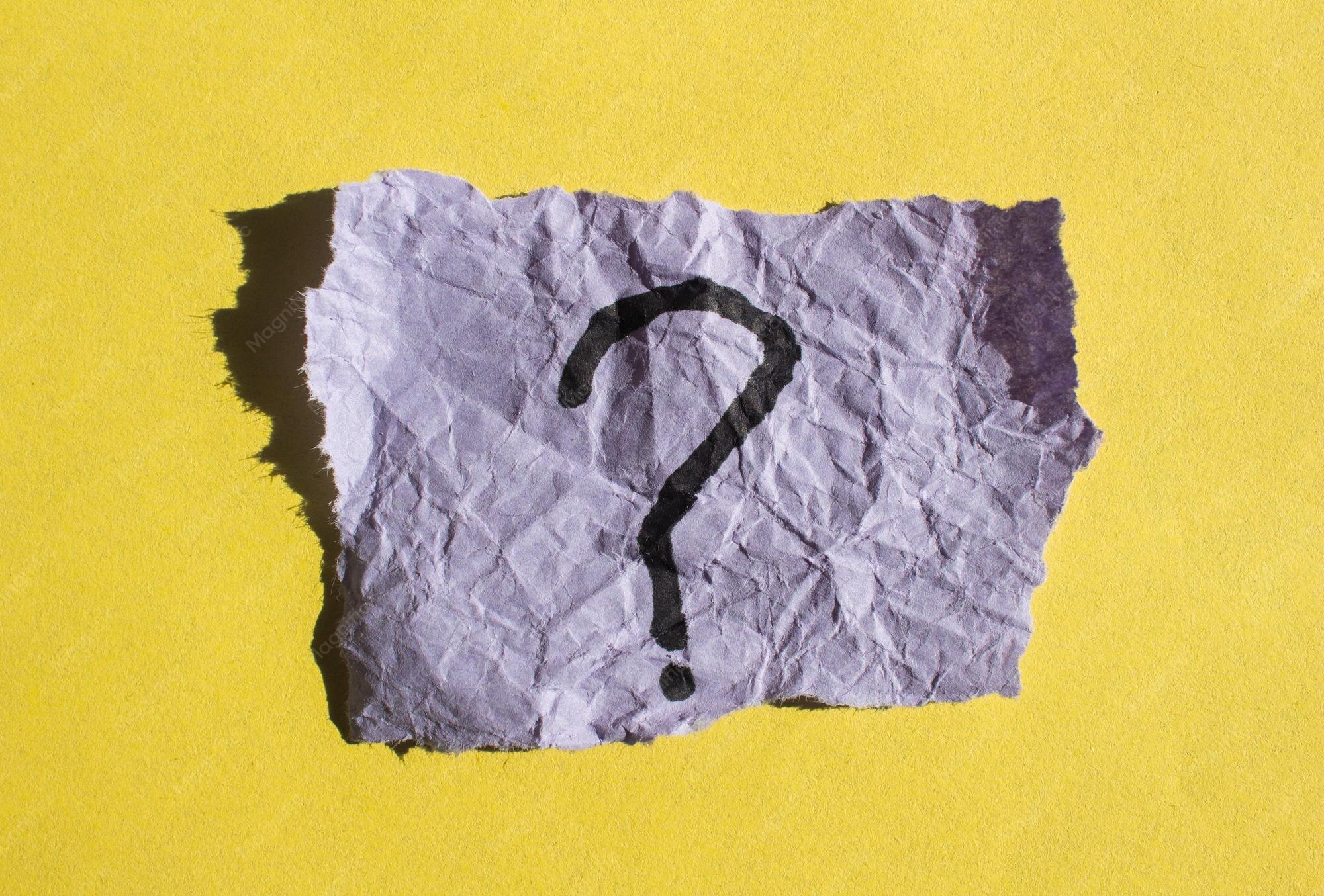 A question mark on a crinkled piece of paper against a yellow background